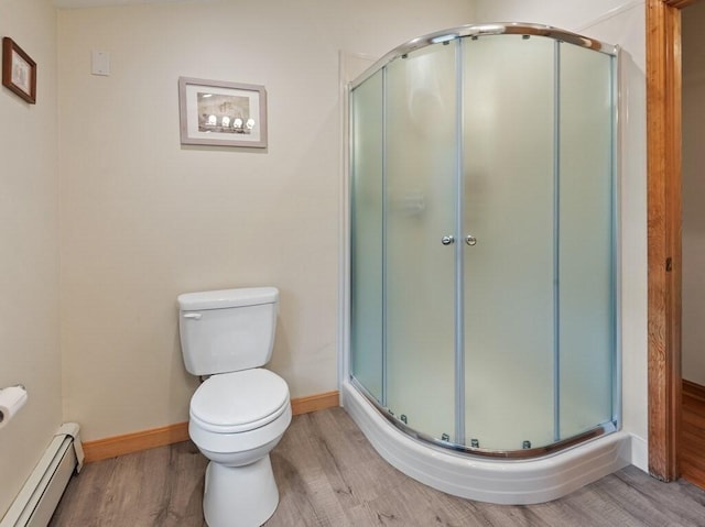 full bath with wood finished floors, toilet, baseboards, a baseboard radiator, and a stall shower