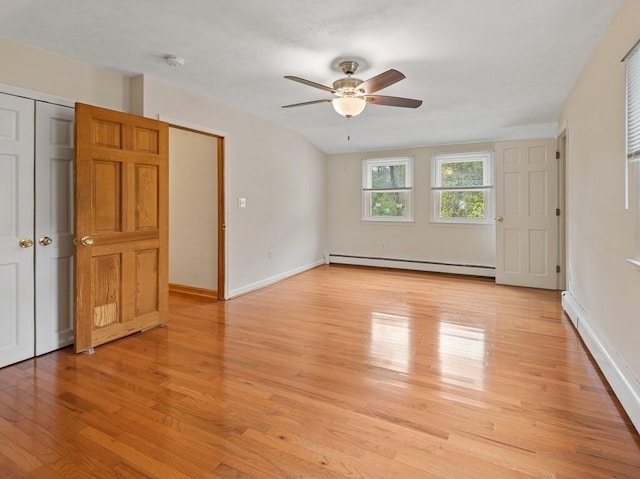 unfurnished bedroom with a ceiling fan, light wood-style floors, baseboards, and a baseboard radiator