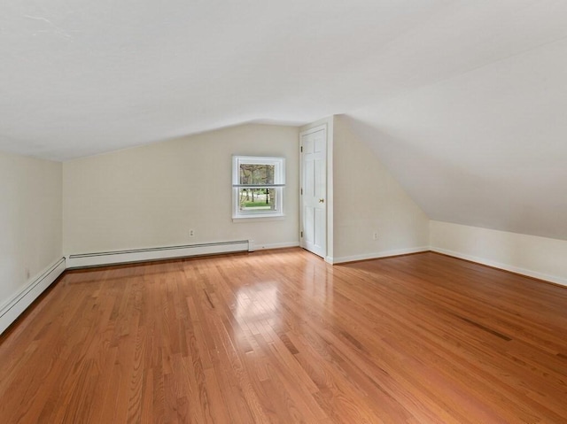 additional living space featuring baseboard heating, light wood-type flooring, baseboards, a baseboard radiator, and lofted ceiling