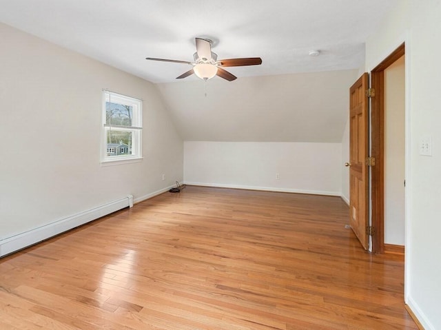 additional living space featuring lofted ceiling, baseboards, baseboard heating, light wood-type flooring, and a ceiling fan