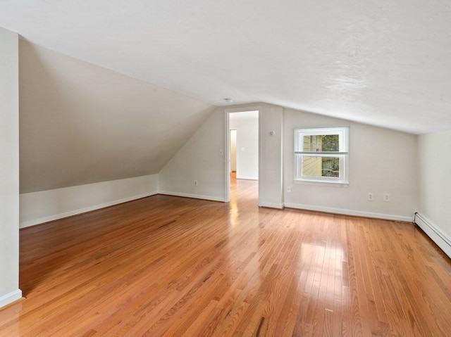bonus room with baseboards, vaulted ceiling, baseboard heating, and light wood-type flooring