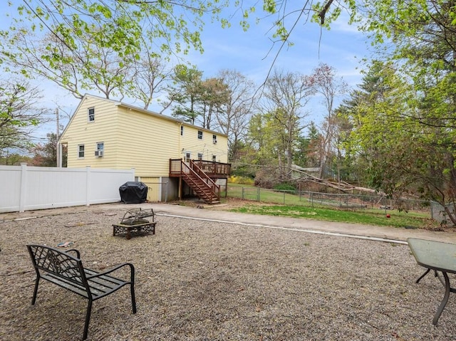view of yard with stairway, a wooden deck, a fenced backyard, and an outdoor fire pit