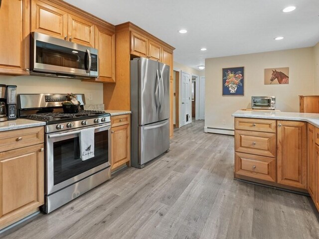 kitchen featuring light wood-style floors, light countertops, appliances with stainless steel finishes, and a baseboard heating unit