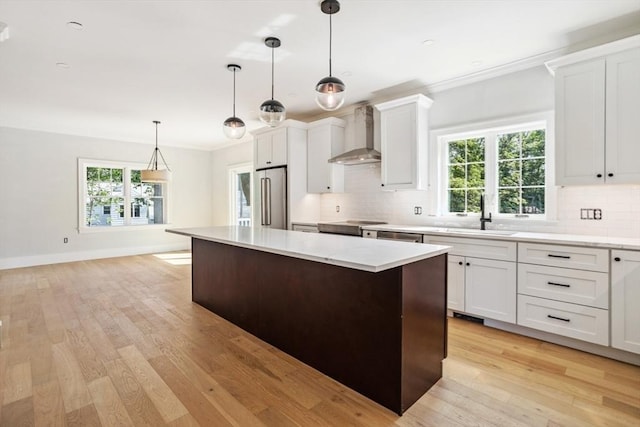 108 S St, Reading, MA 01867 - kitchen featuring wall chimney range hood, stainless steel refrigerator, a center island, backsplash, and ornamental molding