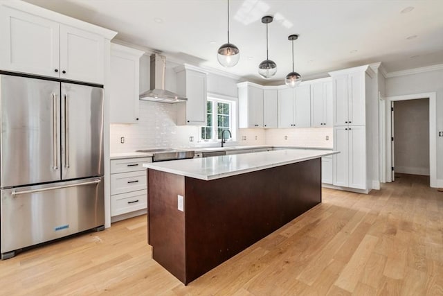 108 S St, Reading, MA 01867 - kitchen featuring high end fridge, wall chimney exhaust hood, crown molding, light wood-style floors, and a kitchen island