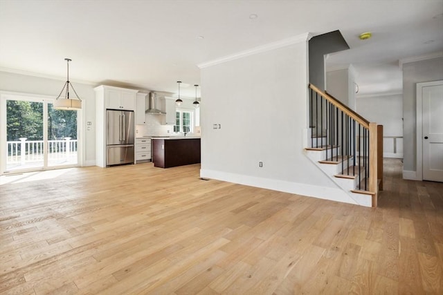108 S St, Reading, MA 01867 - unfurnished living room featuring crown molding, light wood-style flooring, and stairway
