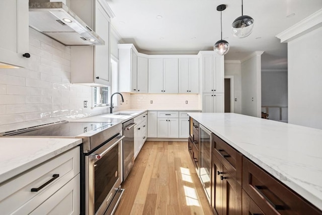 108 S St, Reading, MA 01867 - kitchen featuring appliances with stainless steel finishes, extractor fan, crown molding, light wood-style floors, and white cabinets