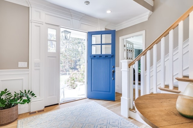 foyer entrance with light hardwood / wood-style flooring and ornamental molding