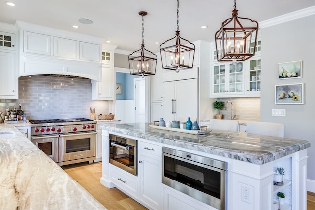 kitchen featuring appliances with stainless steel finishes, white cabinetry, hanging light fixtures, and backsplash