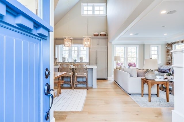 foyer entrance with light hardwood / wood-style floors, a healthy amount of sunlight, high vaulted ceiling, and an inviting chandelier