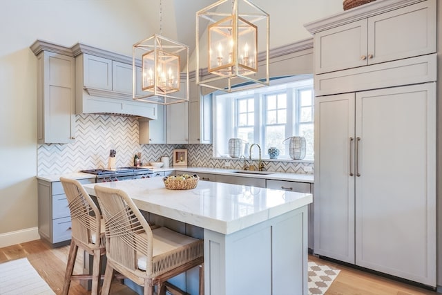 kitchen with a kitchen island, light hardwood / wood-style flooring, hanging light fixtures, sink, and gray cabinets