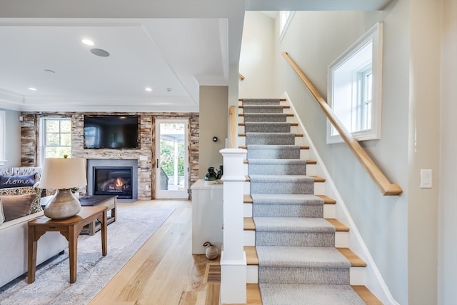 staircase with ornamental molding, hardwood / wood-style floors, and a fireplace