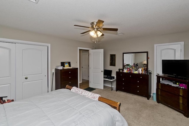 bedroom with light carpet, a textured ceiling, ceiling fan, and a closet