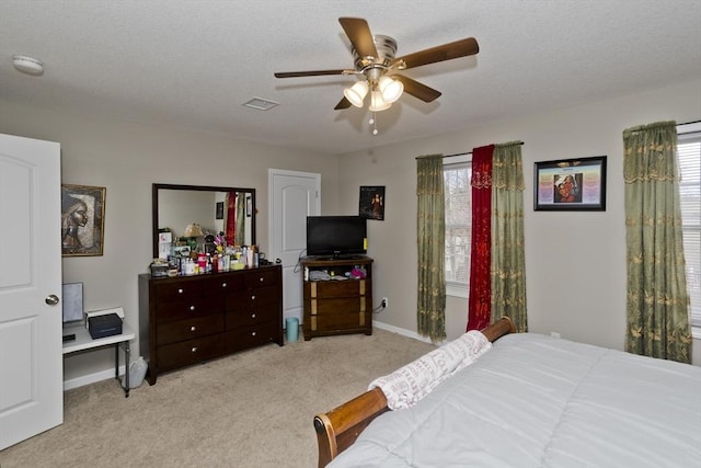 bedroom featuring multiple windows, light colored carpet, and a textured ceiling