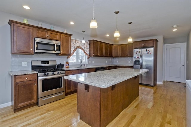 kitchen featuring a kitchen island, appliances with stainless steel finishes, sink, a kitchen bar, and hanging light fixtures