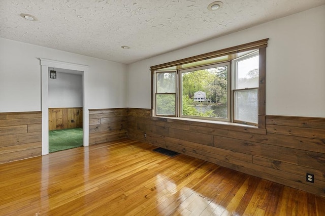 38 Lakeshore Dr, Wayland, MA 01778 - spare room featuring wainscoting, wood walls, light wood finished floors, and a textured ceiling