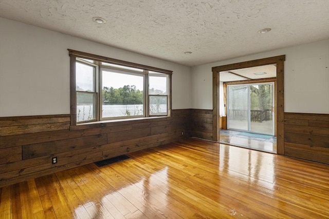 38 Lakeshore Dr, Wayland, MA 01778 - spare room with wainscoting, wooden walls, light wood-style flooring, and a textured ceiling