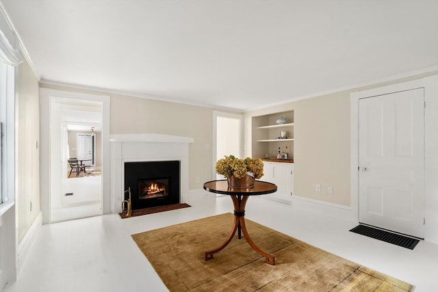 sitting room with a fireplace with flush hearth, crown molding, and built in features