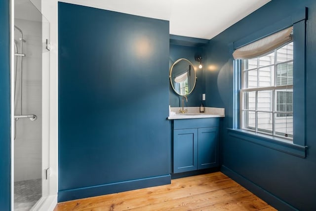 full bathroom featuring a shower, vanity, baseboards, and wood finished floors