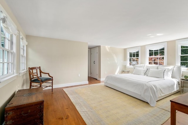 bedroom with multiple windows, baseboards, and wood finished floors