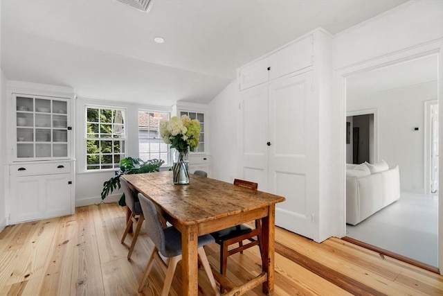 dining room with light wood-type flooring and vaulted ceiling