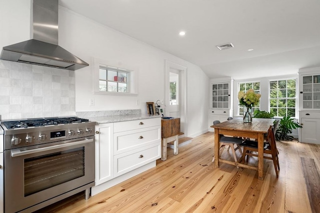 kitchen with range hood, light wood finished floors, visible vents, gas stove, and white cabinets