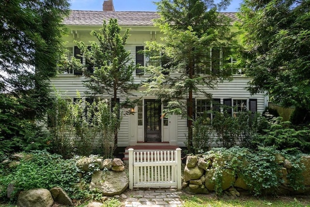 view of front of property with a shingled roof and a chimney