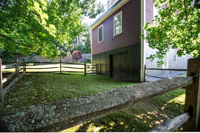 view of side of home featuring a lawn, an attached garage, and fence