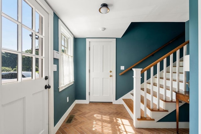 foyer with baseboards, stairs, visible vents, and a wealth of natural light