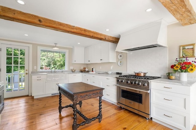 kitchen with premium range hood, white cabinets, beam ceiling, and high end stainless steel range