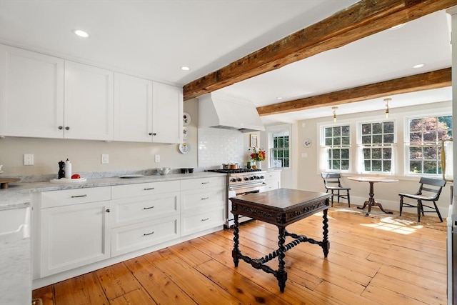 kitchen featuring light stone counters, high end stainless steel range, light wood-style floors, white cabinets, and premium range hood