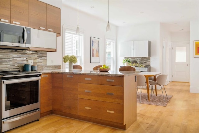 23 Hall Ave Unit 1, Somerville, MA 02144 - kitchen featuring stainless steel appliances, a peninsula, tasteful backsplash, light wood finished floors, and light stone counters