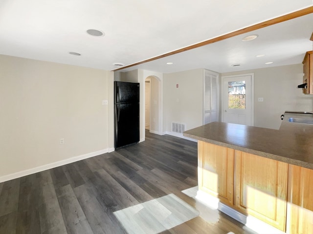 kitchen with light brown cabinetry, black fridge, dark hardwood / wood-style flooring, and sink