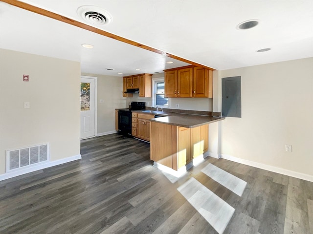 kitchen with dark wood-type flooring, sink, black electric range, kitchen peninsula, and a breakfast bar area