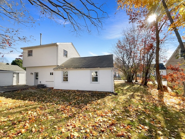 back of house with central air condition unit and a yard