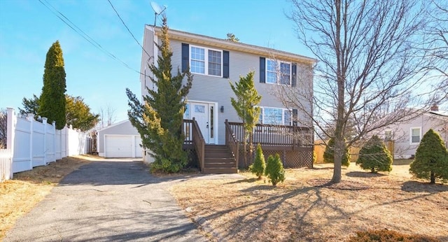 view of front of home featuring a detached garage, fence, aphalt driveway, and an outbuilding