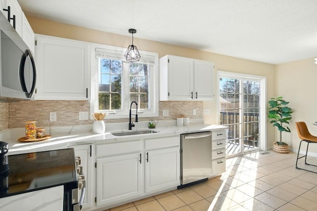 kitchen with light tile patterned floors, appliances with stainless steel finishes, a sink, and decorative backsplash