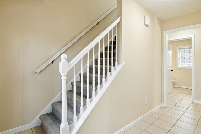 staircase featuring baseboards and tile patterned floors