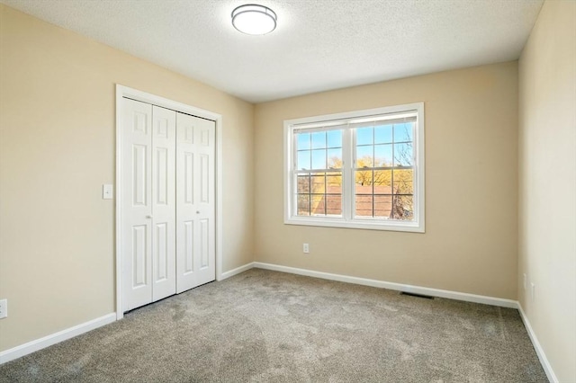 unfurnished bedroom with baseboards, visible vents, a closet, and carpet flooring