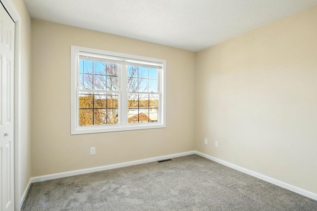 carpeted spare room with visible vents and baseboards