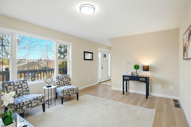 sitting room with visible vents, baseboards, and wood finished floors