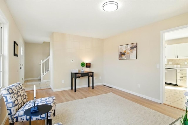 sitting room with baseboards, stairway, and light wood finished floors