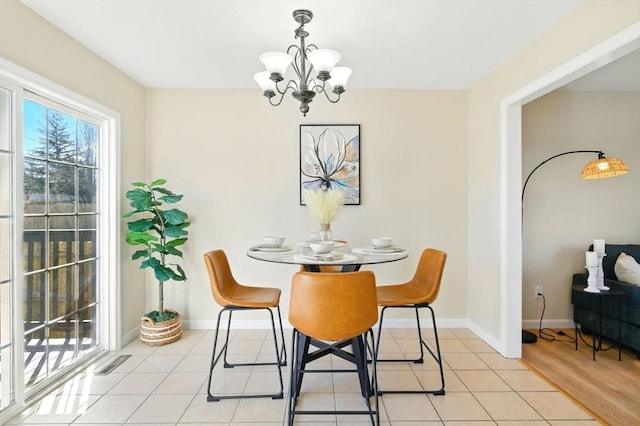 dining area with a chandelier, light tile patterned flooring, visible vents, and baseboards