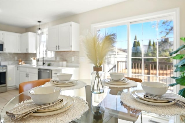 kitchen with white cabinets, range, dishwasher, light countertops, and backsplash