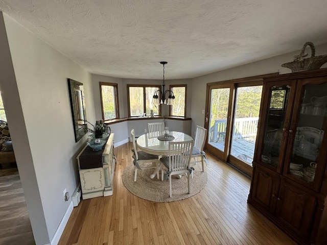 dining space with a textured ceiling, baseboards, a wealth of natural light, and wood finished floors