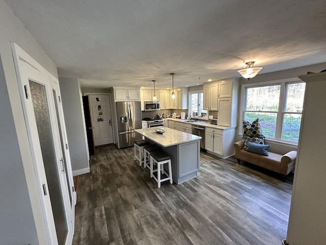 kitchen featuring dark wood-style flooring, a breakfast bar, light countertops, a sink, and stainless steel appliances