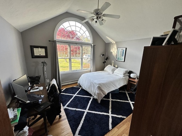 bedroom with lofted ceiling, wood finished floors, baseboard heating, and multiple windows
