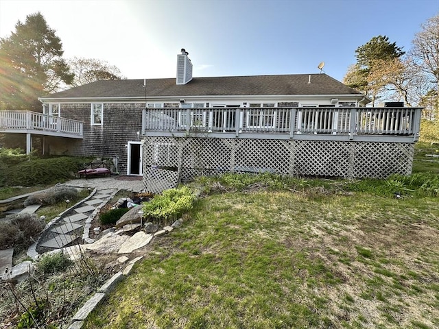 rear view of house featuring a wooden deck, a chimney, and a yard