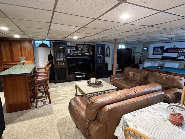living room with a drop ceiling, a dry bar, and light carpet