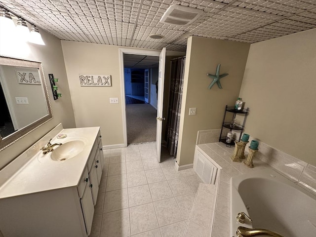 bathroom with vanity, tile patterned flooring, baseboards, and a bath